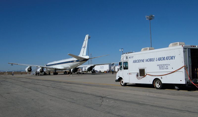 An Aerodyne mobile laboratory sits behind a DC-8 airplane on a tarmac