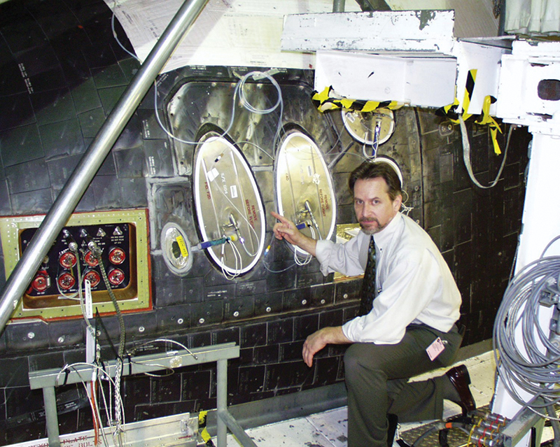 James Doyle kneels to examine thrusters on Space Shuttle Atlantis
