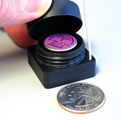 A miniature wireless sensor next to a same sized quarter shown for scale