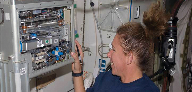 Astronaut inspects water quality monitor on the ISS