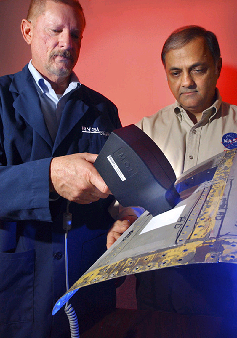 Two men from NASA scan shuttle parts
