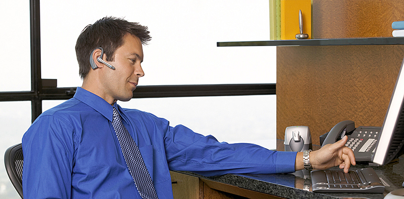 A business man using the Voyager Bluetooth headset