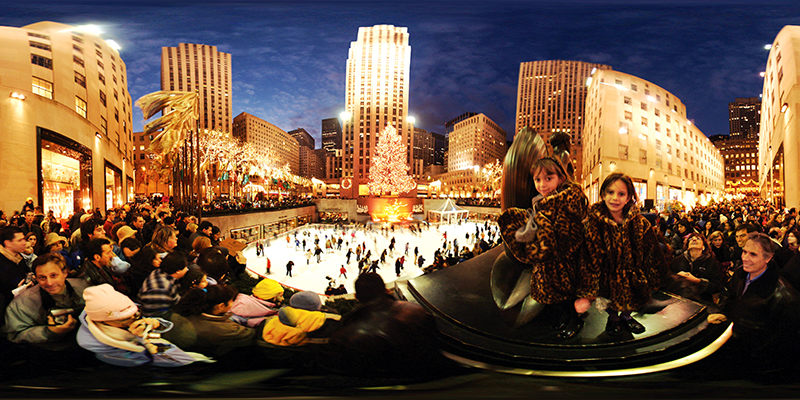 Wide image of ice skaters and visitors to Rockefeller Center