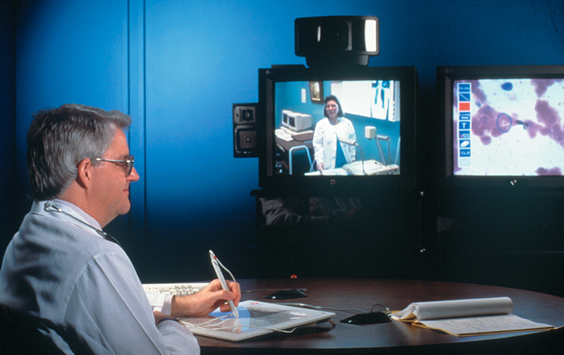 Dr. James Legler views a blood slide by means of video relay