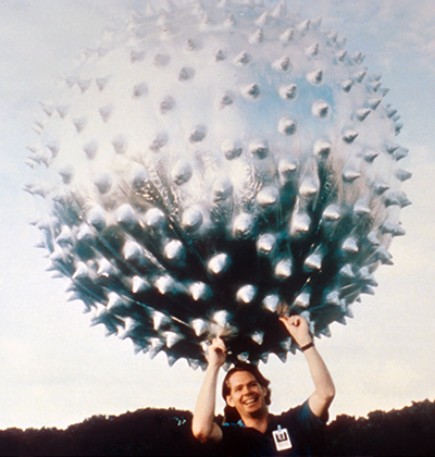A man holding the Jimsphere, which looks like a large spiny metallic ball, above his head