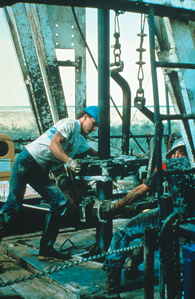 Workers at a Texaco oil field drill a vertical oil well