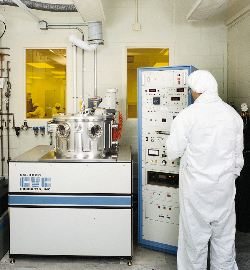 A specialist in a clean suit prepares a system for depositing superconducting thin films