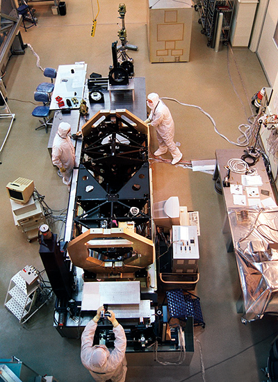 workers assemble a satellite in a clean room environment 