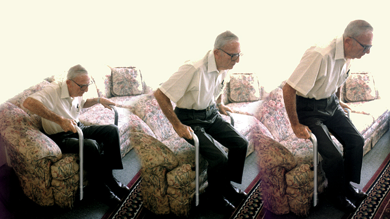 Aan elderly man using the eZ-uP device from sitting to standing position