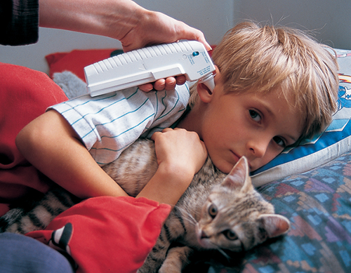 A boy has his temperature taken in ear cavity with Braun's temperature sensor