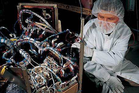 An engineer connects a momentum wheel to a commercial space satellite