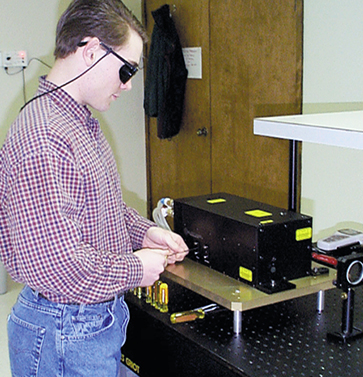 Worker wearing protective glasses and using a laser system