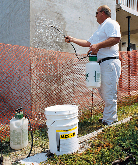 Man treats a concrete wall with a spray-on chemical 