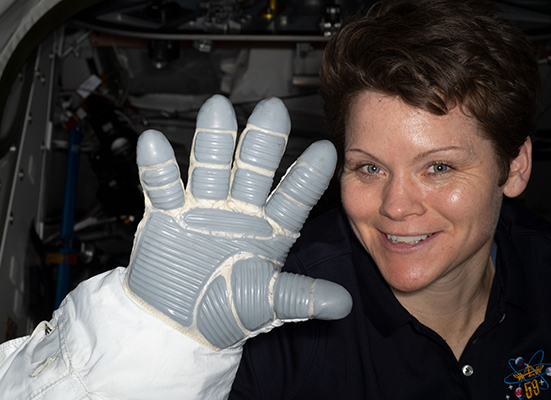 NASA astronaut Anne McClain displays a spacesuit glove that is part of an Extravehicular Mobility Unit, or spacesuit