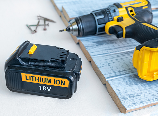 A lithium-ion 18-volt battery next to a cordless drill