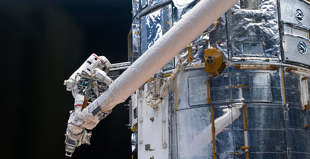 In May 2009, astronaut John Grunsfeld works on repairs to the Hubble Space Telescope, including replacing three thermal blankets protecting the telescope’s electronics