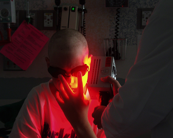 A doctor using a light-therapy device on a patient