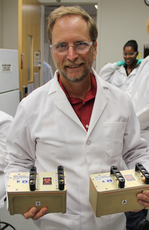 NASA plant scientist Gary Stutte holds two plant experiment modules that flew on the last space shuttle mission in 2011