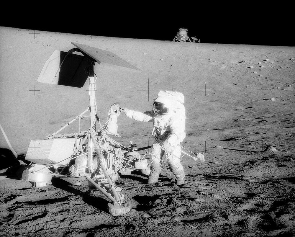 Apollo 12 astronaut Charles Conrad examines the television camera on the Surveyor 3 lunar probe