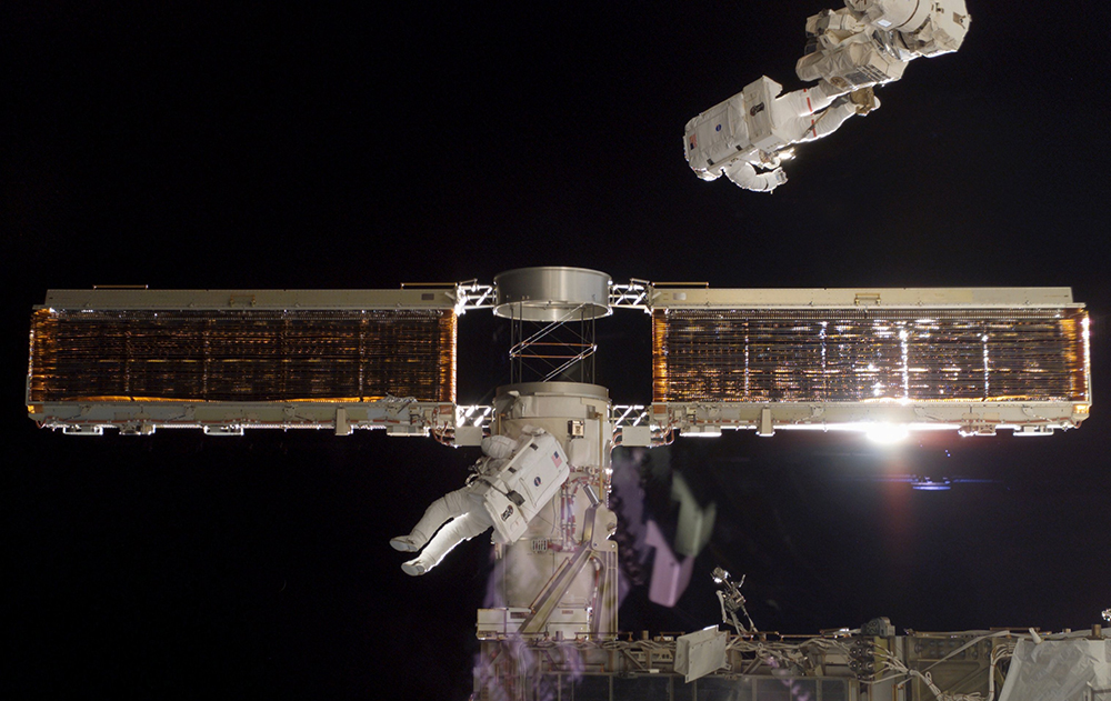 An astronaut works on a collapsible solar panel on the International Space Station