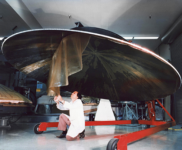 An engineer works on a Voyager spacecraft’s high-gain antenna dish