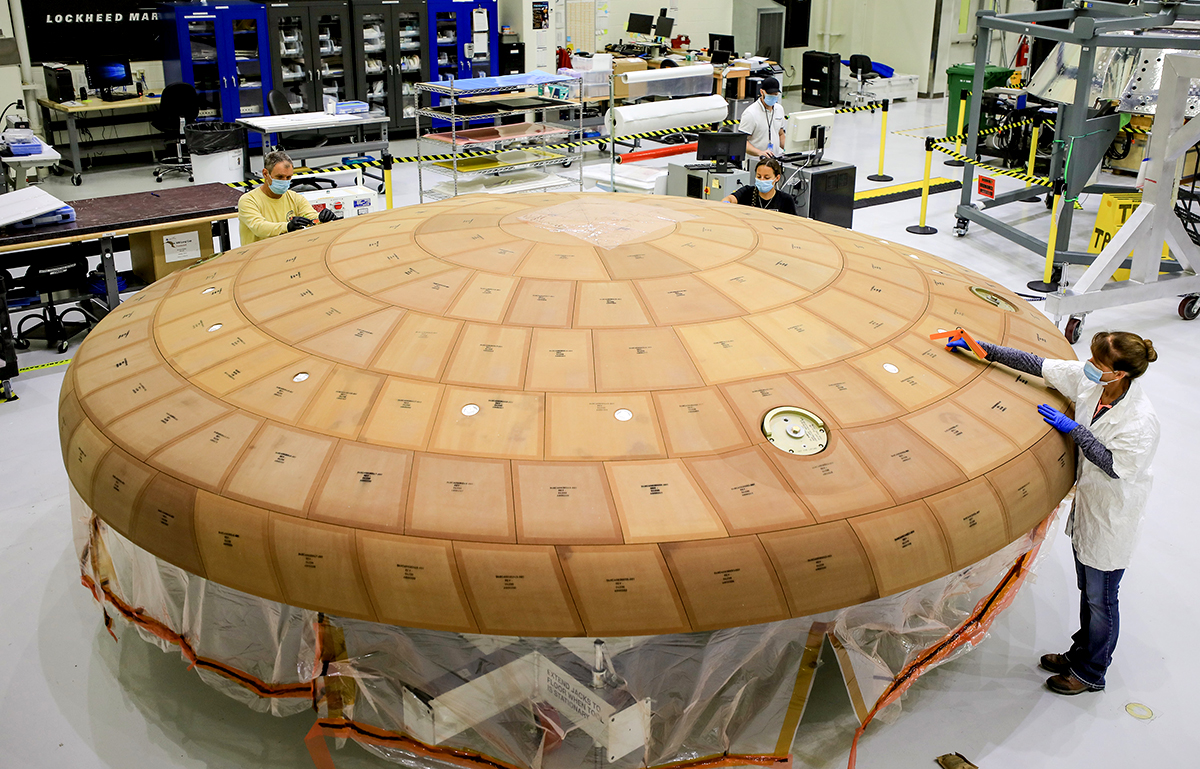 Technicians at Kennedy Space Center finish applying blocks of Avcoat, a lightweight epoxy resin, to the heat shield for the Orion crew module