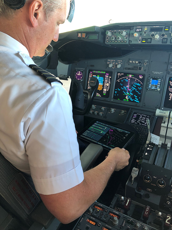 Alaska Airlines Captain Bret Peyton looks at route options presented on a tablet called an electronic flight bag