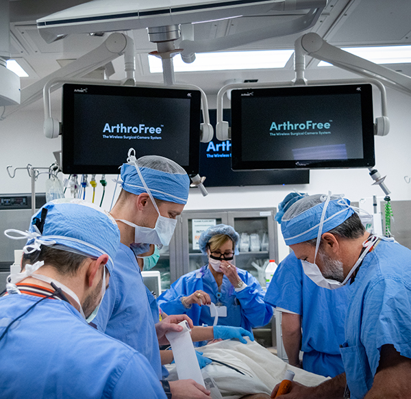 A crowded operating room with ArthroFree on screens
