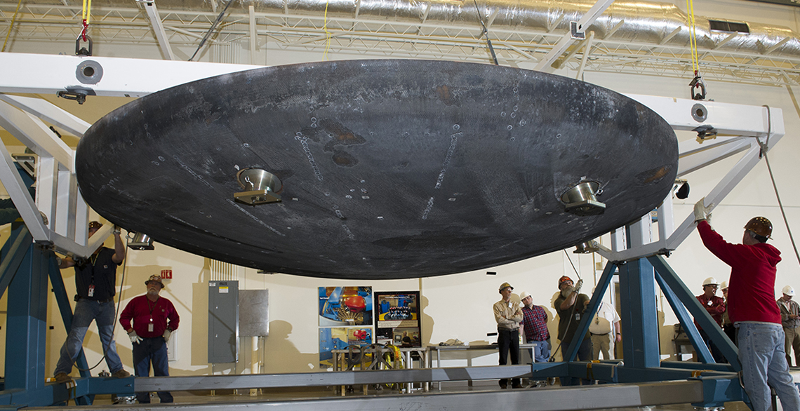 Technicians hoist an Orion heat shield after testing
