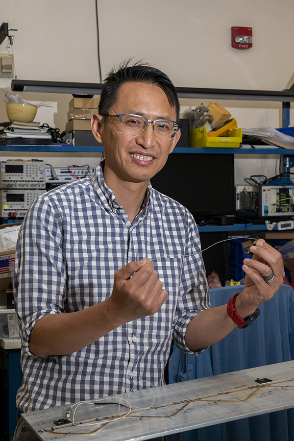 NASA engineer Patrick Chan holds a fiber-optic sensor line