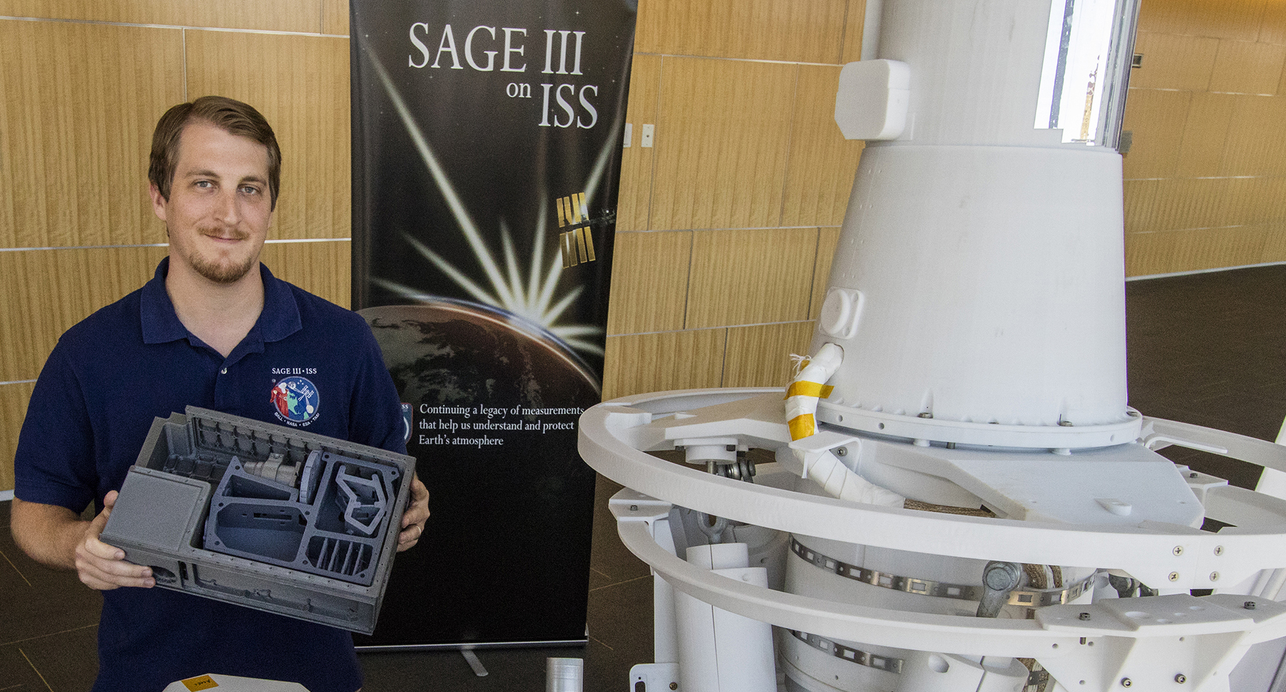 Robert Damadeo of Langley Research Center, co-principal investigator for the SAGE IV satellite, holds a model of the proposed little CubeSat’s bus beside a model of the far larger SAGE III instrument