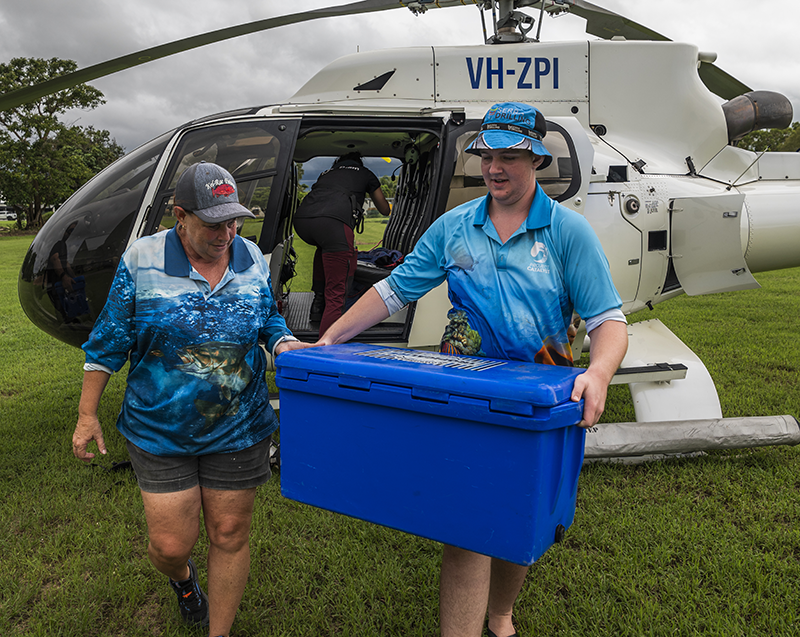 Volunteers unloading coolers from a helicopter