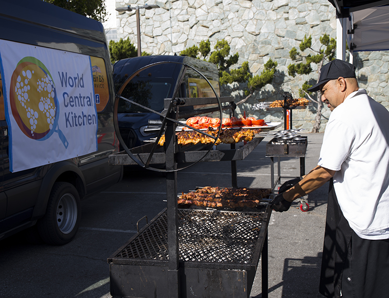 Man grilling food in a sunny parking lot