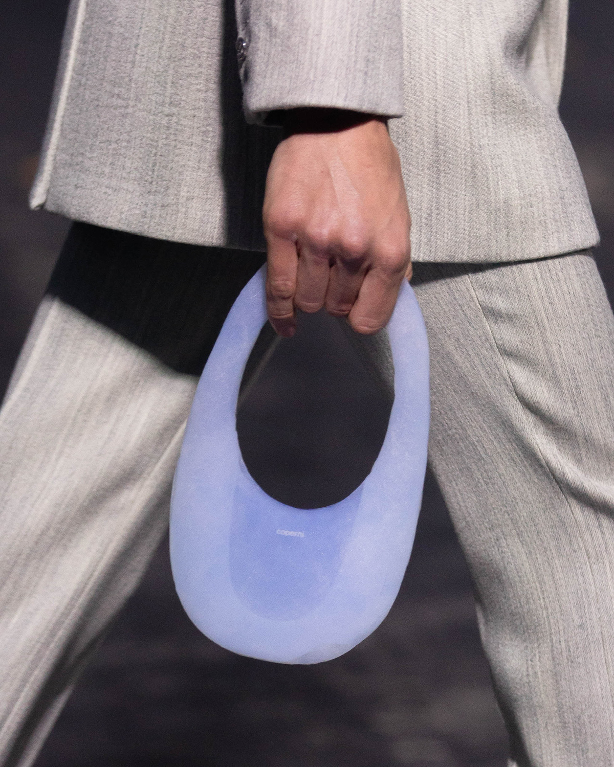 bag in hand of model wearing gray suit