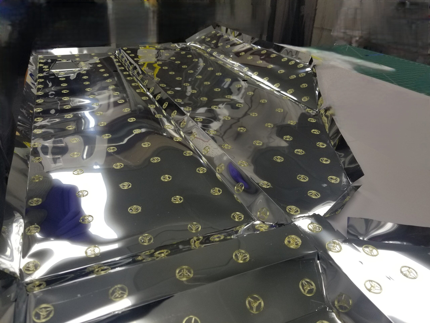 Creased reflective material with regularly spaced attachment disks