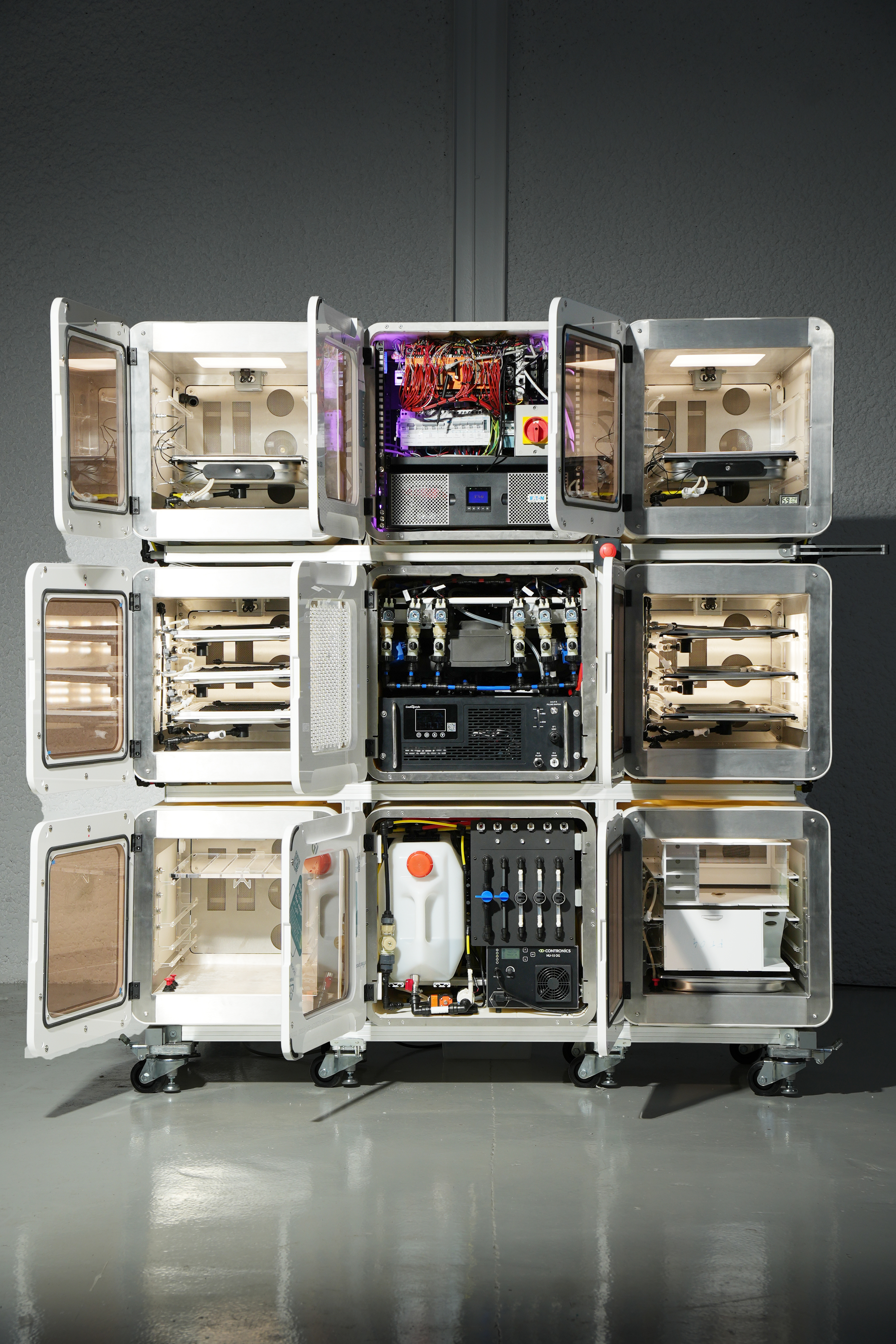 Nine cubes with open doors showing racks of equipment inside them, the bottom cubes are on wheels.