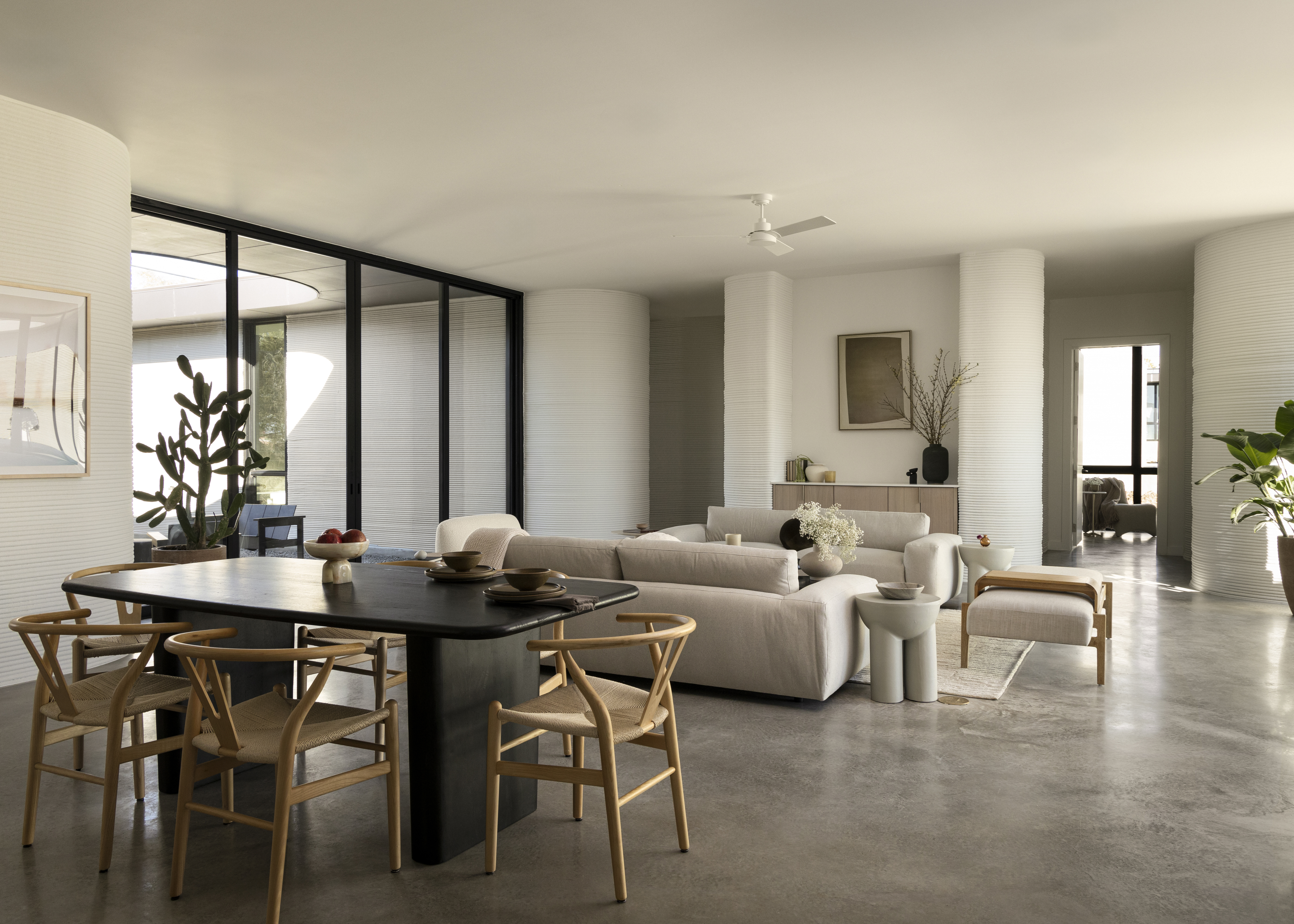Stylish home interior with curved walls, polished concrete floors, and open living and dining spaces with neutral furnishings. 