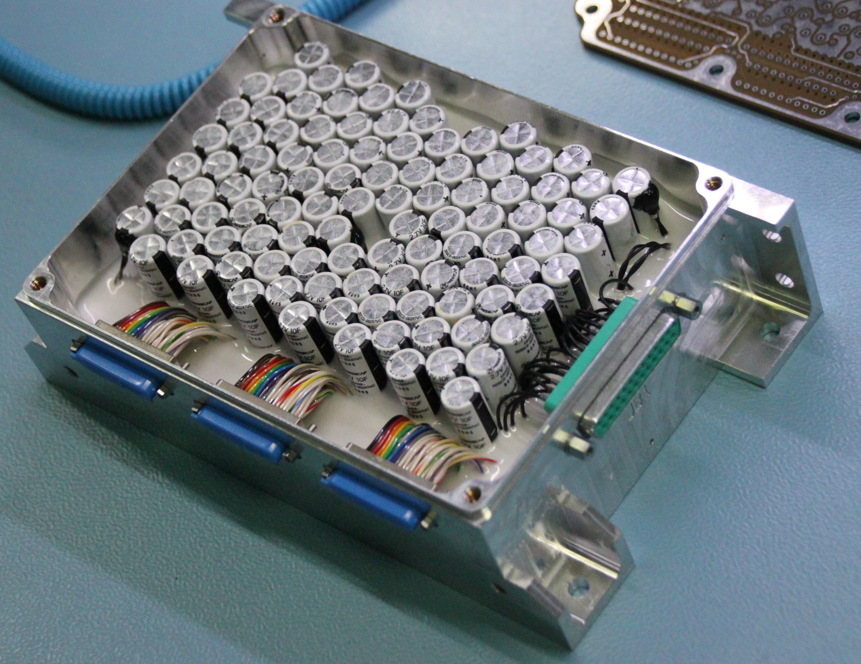 A metal part covered in dozens of tiny cylinders connected by wires.