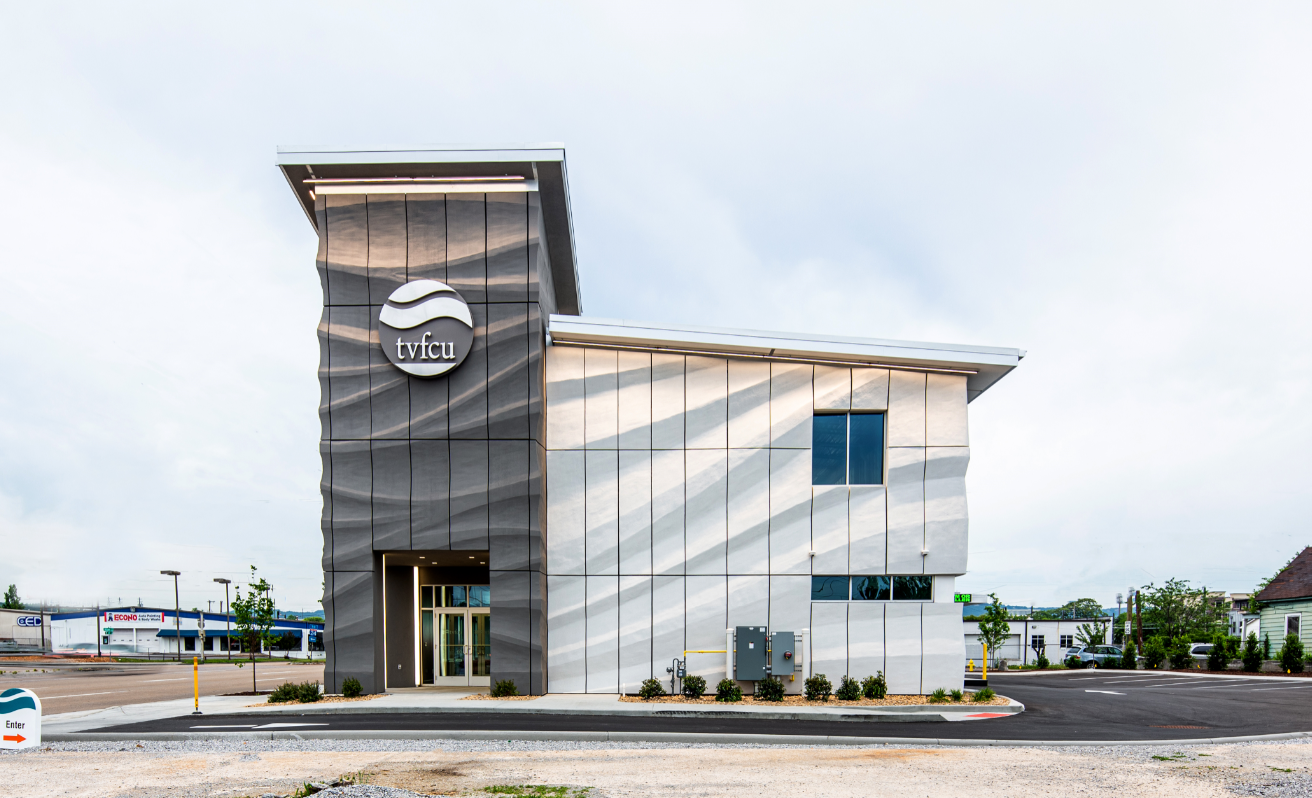 The exterior of a building with wave-like siding and a sign that says “tvfcu.” 