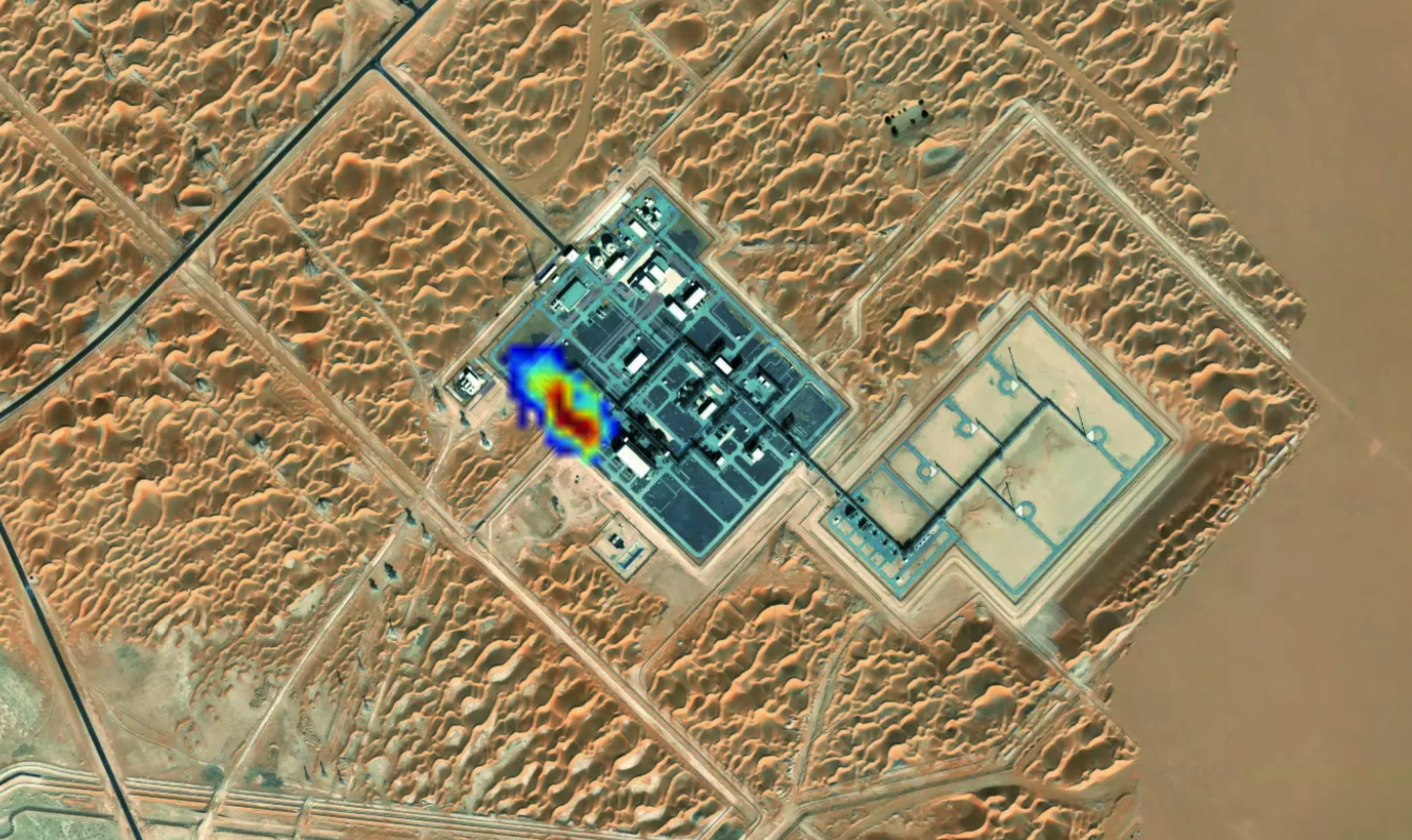 A birds-eye view of an oil field, with a bloom of color over one small section