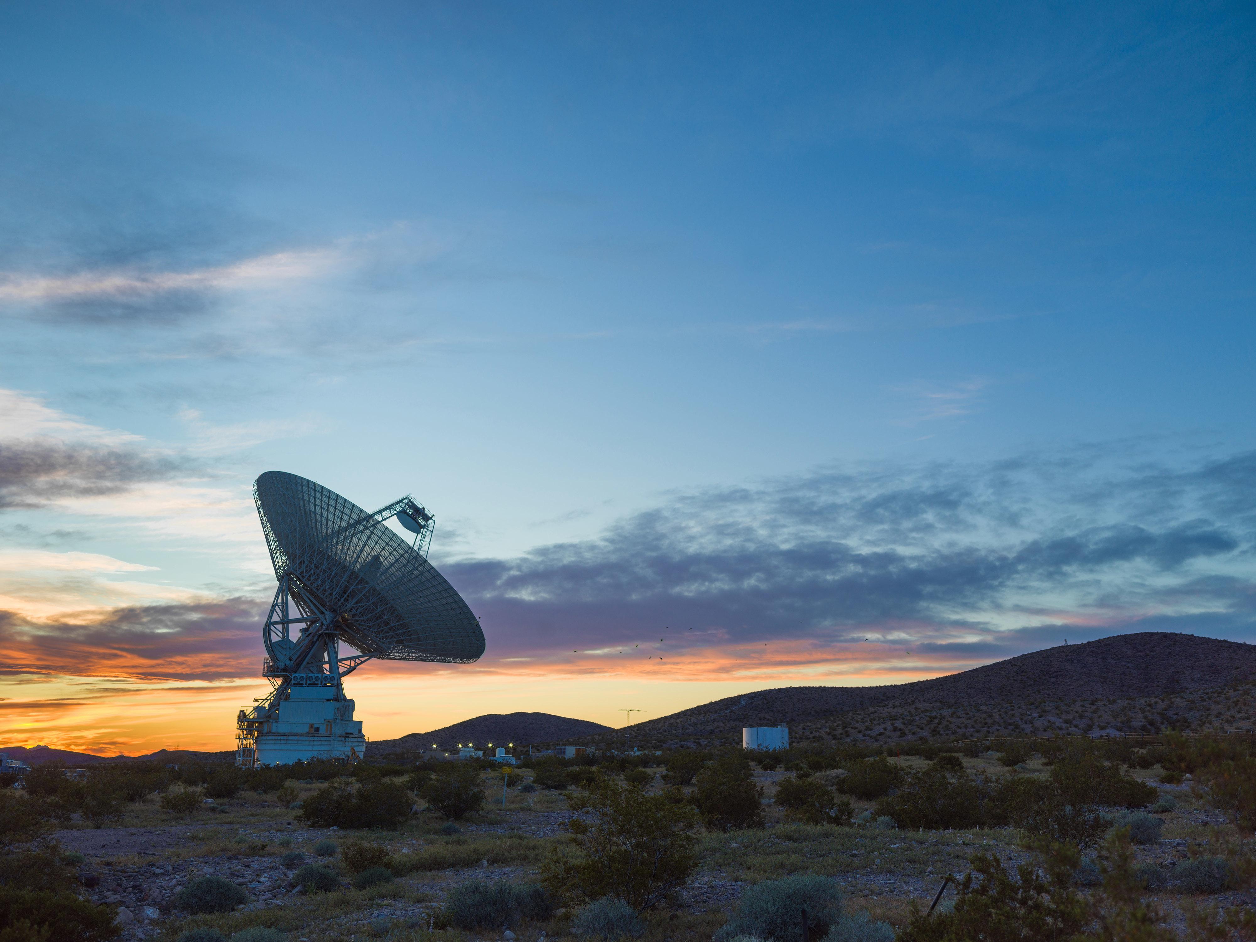 	A radio antenna dish pointed to the sky at twilight.