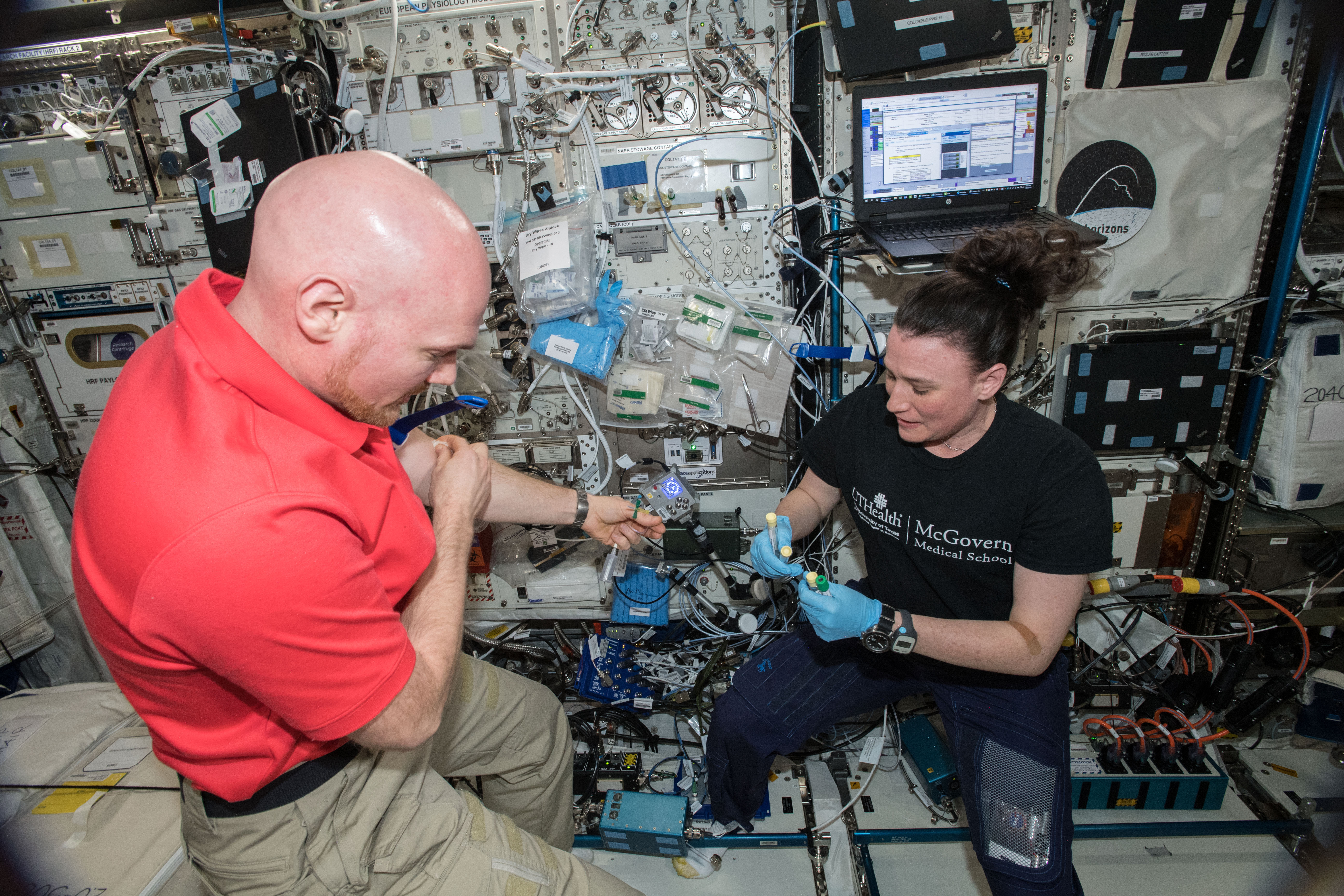 European Space Agency (ESA) astronaut Alexander Gerst and NASA astronaut Serena Auñón-Chancellor, drawing blood samples in the Columbus Module on the International Space Station.