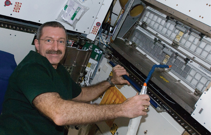 Astronaut Dan Burbank cleans cabin air filters on the space station