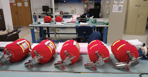 Red fire extinguishers lie in a row on a table in a lab