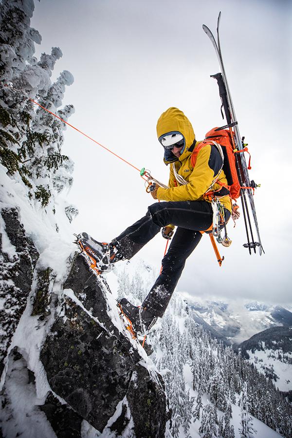 A skier repels down a snowy mountainside