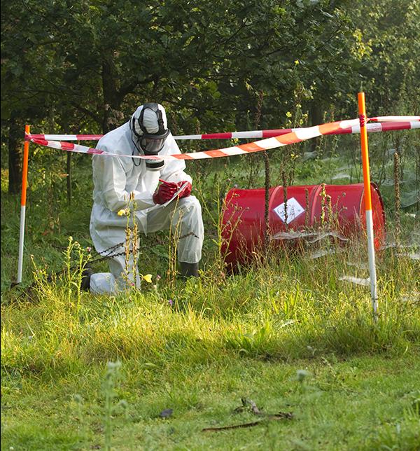 A field worker and a toxic barrel in a marked cleanup zone