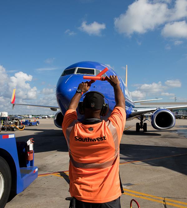 A Southwest Airlines crew member directs a plane on the tarmac
