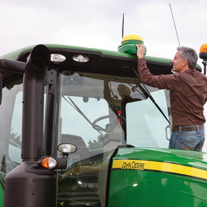 Man installing GPS navigation device on John Deere tractor