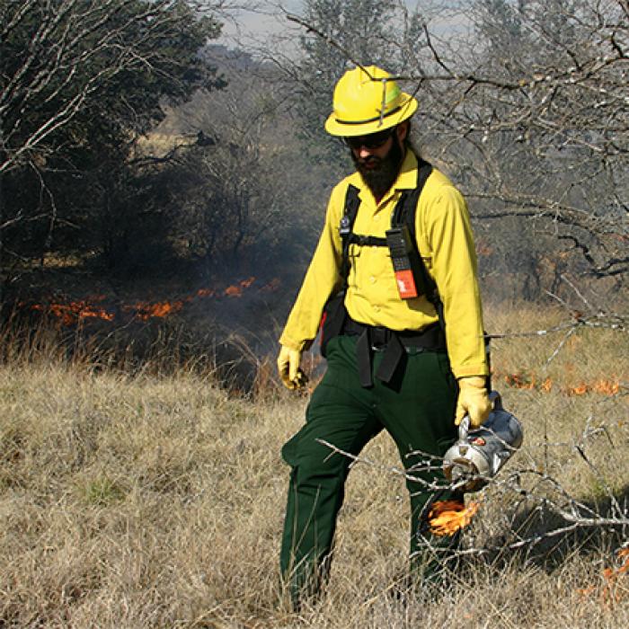 Fire management worker starting a controlled burn
