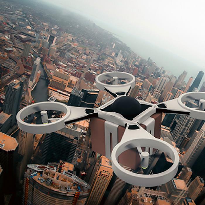 A quadcopter drone carrying a cardboard box over a city